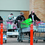 People push full shopping carts outside a store in Watford, England, after new nationwide COVID-19 restrictions were announced last week. The increased restrictions, which were imposed across Europe in an effort to control soaring infection numbers, took a major toll on markets. | Reuters/Paul Childs photo