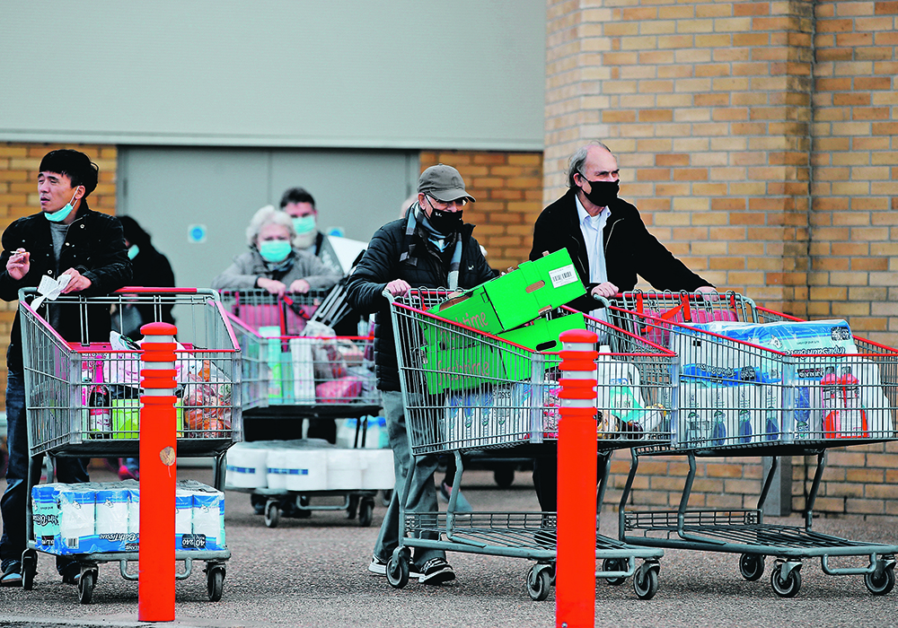 People push full shopping carts outside a store in Watford, England, after new nationwide COVID-19 restrictions were announced last week. The increased restrictions, which were imposed across Europe in an effort to control soaring infection numbers, took a major toll on markets. | Reuters/Paul Childs photo