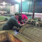 Raymond Dan Menard, left, and his son, Max, of Smoky Trout Farms take a look at the drum filter in their fish barn. The filter is a key component of the farm’s recirculating aquaculture system. | Menard family photo