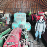 Marv Vassberg of Bawlf, Alta., stands in his shed with some of the dozens of tractors, cars and trucks he has rebuilt. | Mary MacArthur photo