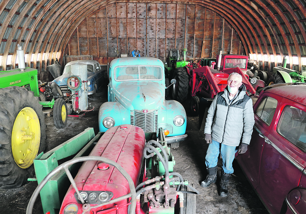 Marv Vassberg of Bawlf, Alta., stands in his shed with some of the dozens of tractors, cars and trucks he has rebuilt.  |  Mary MacArthur photo