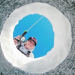 Tasha Eaglesham poses for a portrait through a partially drilled hole in the ice. | Mike Sturk photo