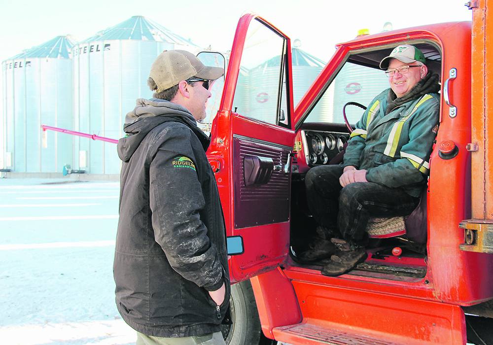 Blake Brownridge, left, talks to local farmer Lyle McLaren while McLaren picks up feed from Brownridge at Ridgeline Agriservices east of Arcola, Sask. | Christalee Froese photo