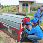 Cheryl Wozny fills the nesting boxes with straw while Angela Balgobin and her children, Annabelle and Nathaniel, look on. | Mary MacArthur photo