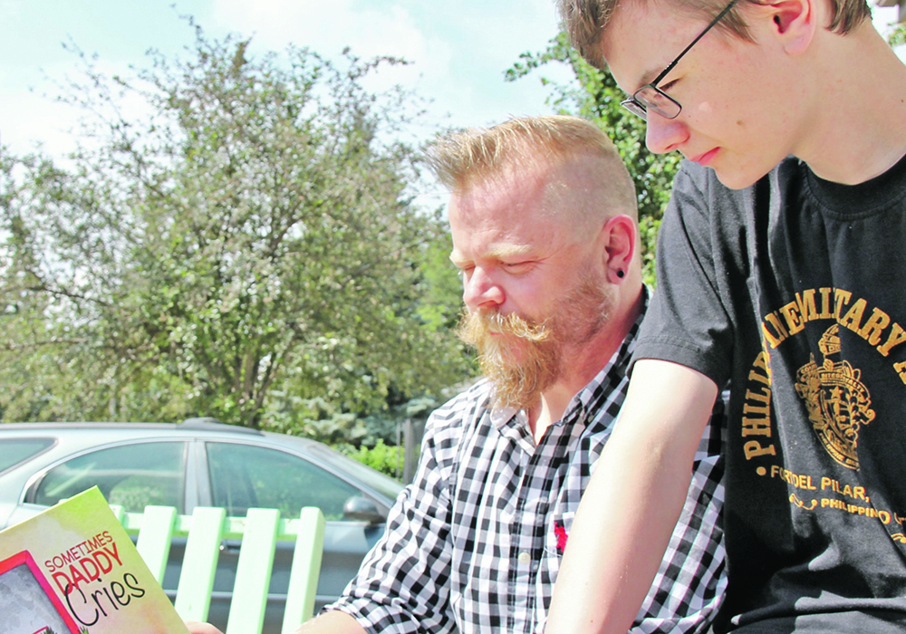 Todd and Jack Rennebohm look at the book Todd wrote to help children cope when their parents deal with mental health challenges. | Christalee Froese photo