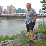 Don Gregorich watches the Bow River flow through Calgary with the Peace Bridge and downtown condo towers in the background. He says moving to the city has brought new opportunities. | DOUG FERGUSON PHOTO