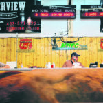 Medicine Hat Feeding Company auctioneer Darren Lutz is flanked by Fred Verhaest and Cindy Dennis during the auction market’s bull sale on Aug. 4. | Alex McQuaig photo