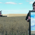 Jill Mitchell, a project ambassador with Grow Hope Saskatchewan, holds the painting, “Feeding the World — One Grain at a Time” that was auctioned off during harvest at the
charity’s project near Bruno, Sask. | Mennonite Central Committee photo
