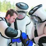 Jake Bodart, left to right, Austin Johnson and Jessica Rendon of the Oregon Department of Agriculture look at the advanced telemetry system used for tracking Asian giant hornets while wearing hornet extraction suits, during a hornet field training day held by the Washington State Department of Agriculture Pest Program near Blaine, Washington last month. | Reuters/Lindsey Wasson photo