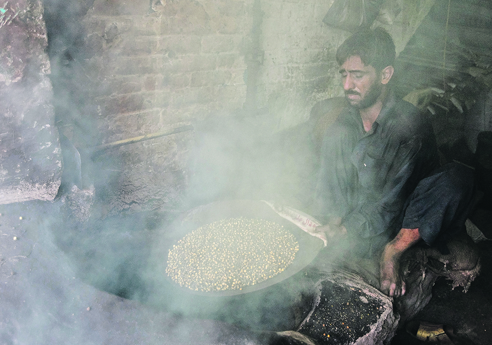 A man roasts chickpeas in an oven at a workshop in Rawalpindi, Pakistan. The crop is an important food in many parts of the world, and new research aims to improve production. | Reuters/
Faisal Mahmood photo