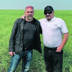Robert Andjelic, right, and his son, Steven, tour of one of their tenants’ canola fields near Melville, Sask., last summer. He said significant portions of the province had good crops that generated enormous profits, which will help support land values this year. | Supplied photo