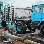 A farm worker at a tractor yard in the village of Yakovlivka outside Kharkiv, Ukraine, looks at a rocket that had landed in a field earlier this month after it was hit by an aerial bombardment. | Reuters/Thomas Peter photo