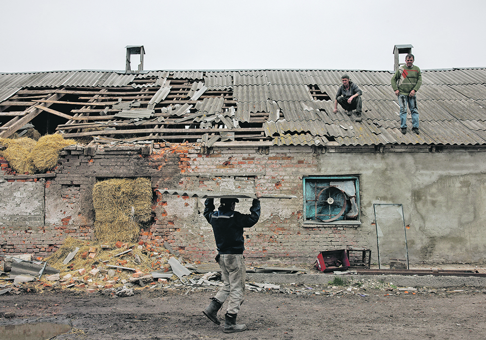 Workers repair the roof of a farm building that was damaged by a mortar during Russia’s attack on Ukraine. The U.S. Department of Agriculture believes there will be a 30 percent destruction/abandonment rate for wheat production in conflict zones, largely because of mined fields, unworkable craters created by bombs, debris in fields and lack of fuel or manpower.  |  Reuters/Alkis Konstantinidis photo