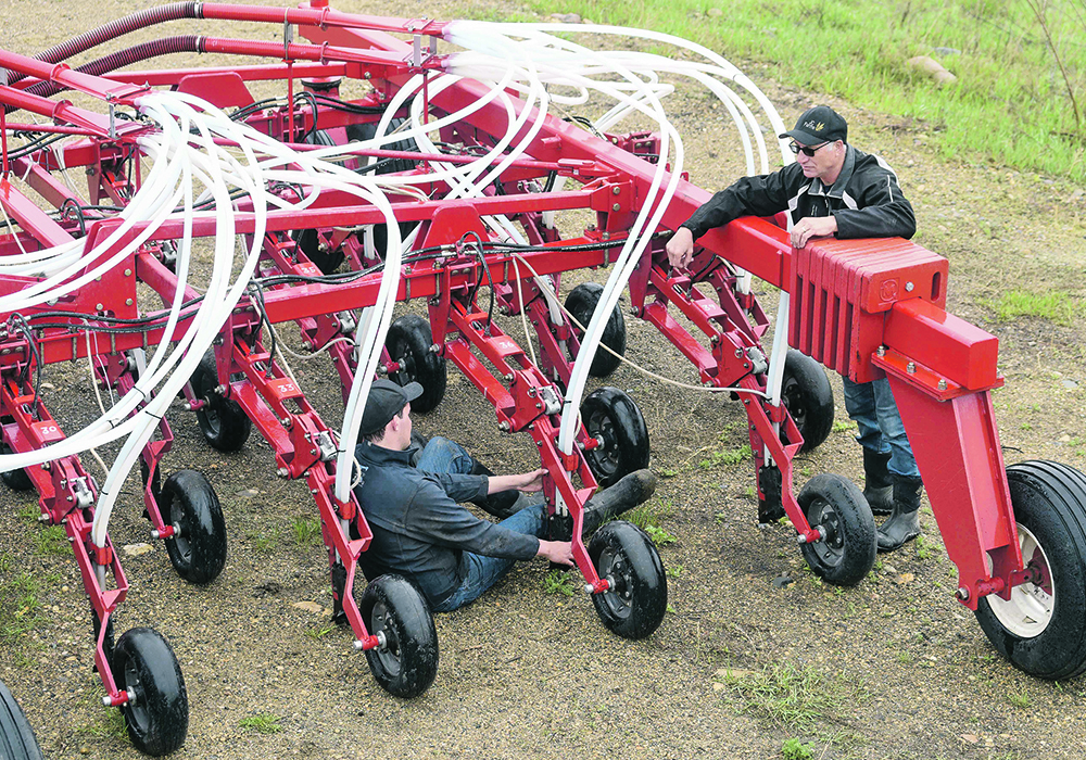 Jocelyn, left, and Jean Decorby perform maintenance on their seed drill on a rainy day this spring.  |  William DeKay photo