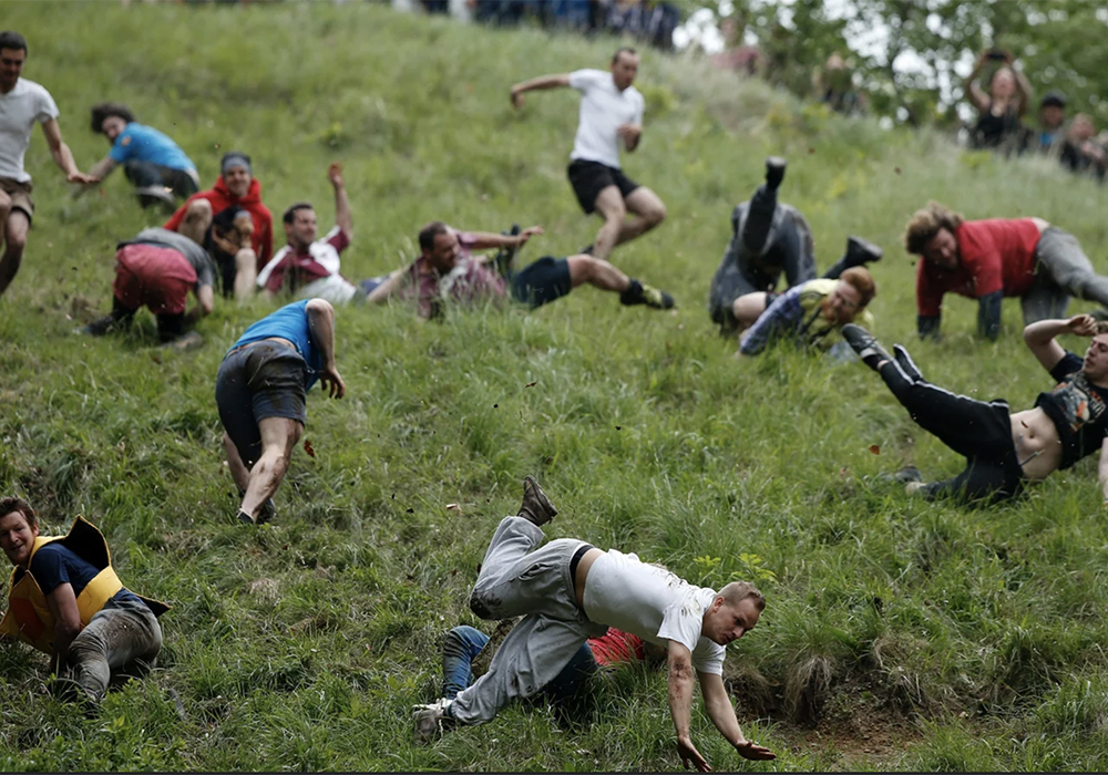 Every year in Gloucester, England, a group of folks with very little fear reflex gather at the top of a steep hill that’s said to have a gradient of 50 percent. Someone tosses out a wheel of double Gloucester cheese and within seconds of its rolling start, the mob begins its race to the bottom. | Screencap via npr.org/Adrian Dennis/AFP/Getty Images