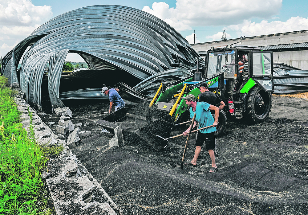 Employees recover rapeseed July 27 from a storage bin destroyed by a Russian military strike in the village of Yulivka in Ukraine’s Zaporizhzhia region. The country is poised to export 2.43 to 2.61 million tonnes of rapeseed/canola this year, which is down only slightly from the 2.72 million tonnes shipped out in 2021-22.  |  Reuters/Dmytro Smolienko photo