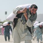 Many countries cut aid to Afghanistan following the fall of Kabul to halt the flow of money to the Taliban, which is considered a terrorist organization. However, the authors say this decision has caused suffering for innocent Afghans in the midst of a humanitarian crisis of massive proportions.  These men carry sacks of rice that were part of humanitarian aid sent by China in April.  |  Reuters/Ali Khara photo