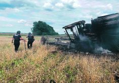 Emergency workers are ensuring it is safe near a burning combine that set off a mine in a wheat field near the village of Vilkhivka, in the Kharkiv region.  |   State Emergency Service of Ukraine photo via Reuters