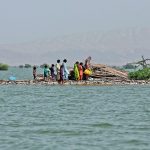 A woman and children take refuge along a damaged road amid flooding that has devastated Pakistan in recent weeks. The Canadian Foodgrains Bank has focused its efforts on helping people displaced from their homes by the flooding. | Reuters/Akhtar Soomro photo