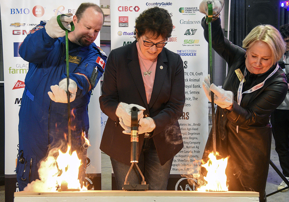From left Darcy McKay, STARS  flight paramedic, Kim Hextall, president of Canadian Western Agribition and Andrea Robertson, CEO of STARS Air Ambulance burn the brand at this year's event.  |  William DeKay photo