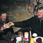 Stepan Kovalyov, 80, and his brother, Volodymyr Kovalyov, 77, toast with horilka, a Ukrainian spirit, inside a cellar where Stepan and his wife live after their house was destroyed during the Russian occupation of their village northwest of Kherson, Ukraine. | Reuters/Nacho Doce photo