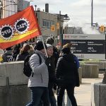 PSAC workers on strike carry a PSAC flag in front of a federal government building in London, Ontario, April 19, 2023.