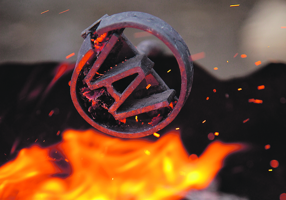 The Agribition logo branding iron positioned over flames.