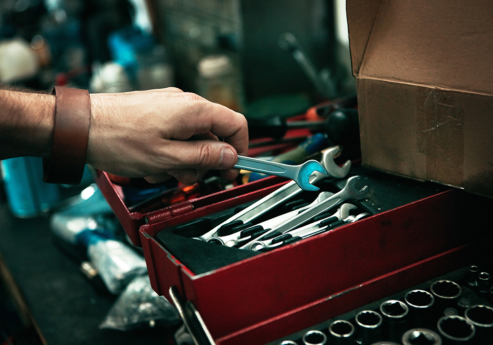 Close-up of a hand picking up a wrench from a tool kit.