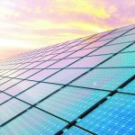 Close-up of a massive array of solar panels, the sun is setting in the background.