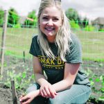 Close-up of a young woman kneeling in a garden.
