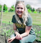 Close-up of a young woman kneeling in a garden.