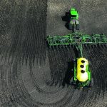 Drone shot from directly overhead as a tractor pulling an air seeder makes a 180-degree trun at the headlands.