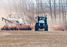 A tractor is just making a turn at the end of a field pulling an air seeder rig.