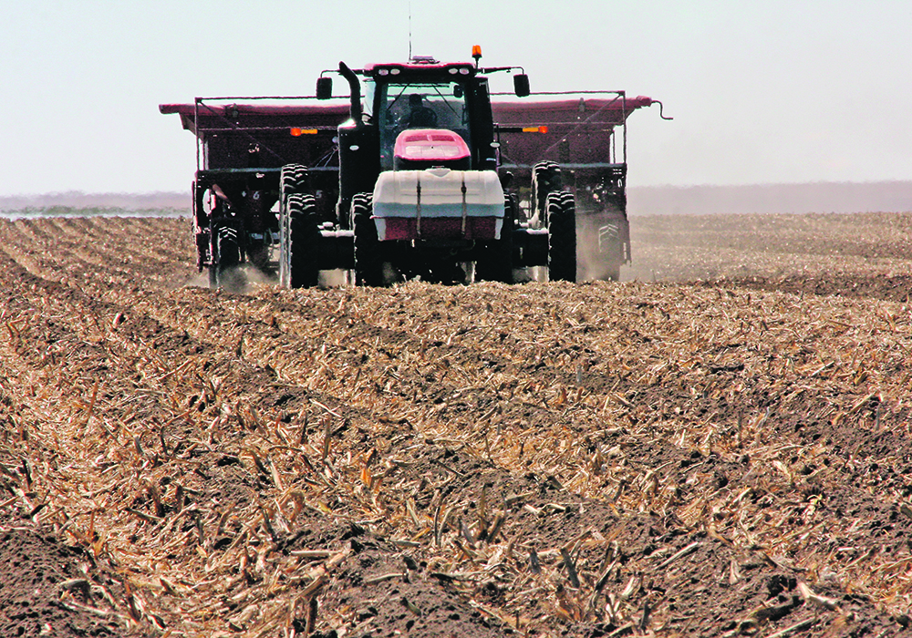 A tractor with a seeder attached plants potatoes.