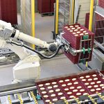 A robot moves a stack of trays with baked goods on them.