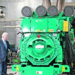 U.S. president Joe Biden looks at a large, green piece of equipment at the Cummins Power Generation Facility in Fridley, Minnesota.