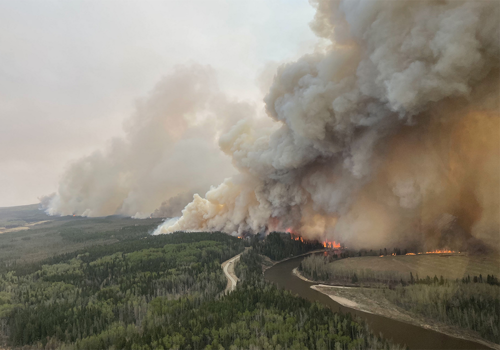 An aerial photo of a massive fire in the forest in Alberta. Smoke rises hundreds of feet into the air.