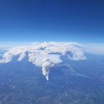 Aerial photo from high over Alberta. White smoke billows high into the sky from a handful of different fires visible below.