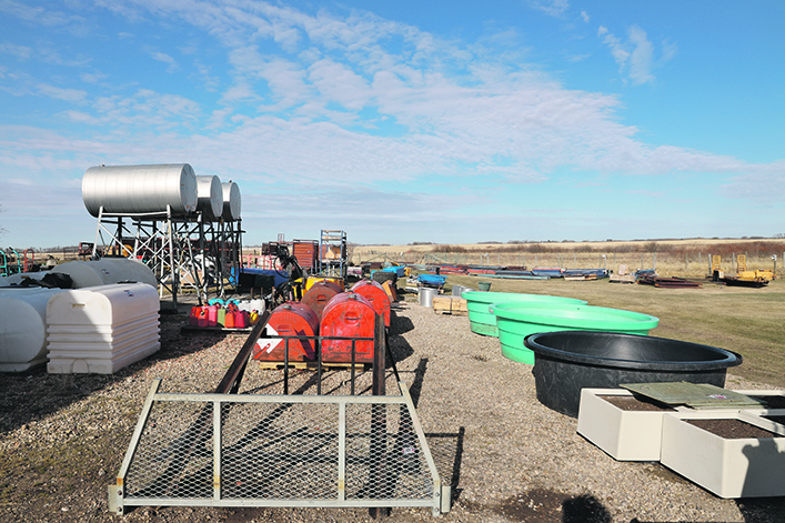 Larger auction items are lined up outside, like bulk fuel tanks and stock water bowls.
