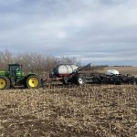 An air seeder is being pulled by a large John Deere tractor.