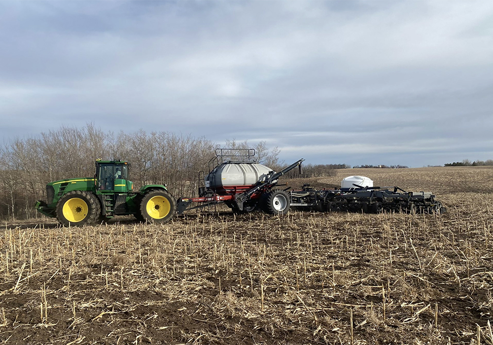 An air seeder is being pulled by a large John Deere tractor.