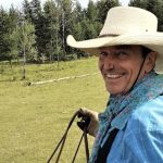 A photo of Reg Steward from AgSafe B.C. on horseback, looking over his shoulder and smiling.