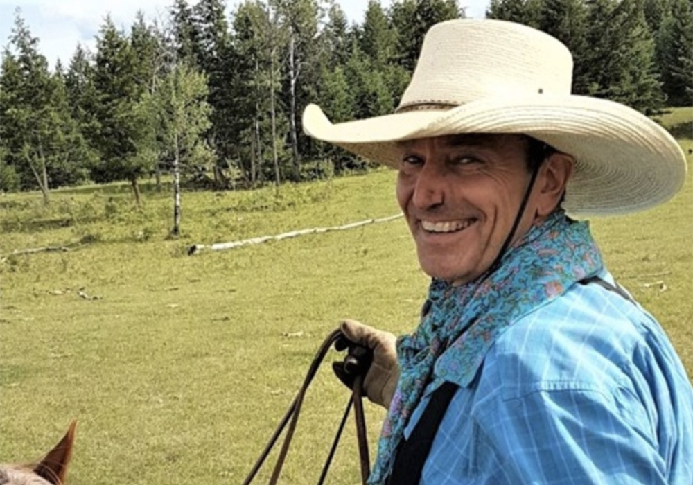 A photo of Reg Steward from AgSafe B.C. on horseback, looking over his shoulder and smiling.