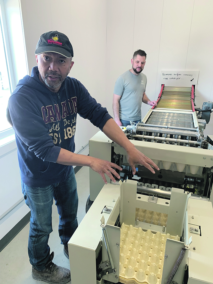 Two men work with an automatic egg packing machine at the Manitoba Egg Farmers Learning and Research Centre in Glenlea, Man.