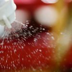 Close-up of a sprayer nozzle with liquid spraying out.