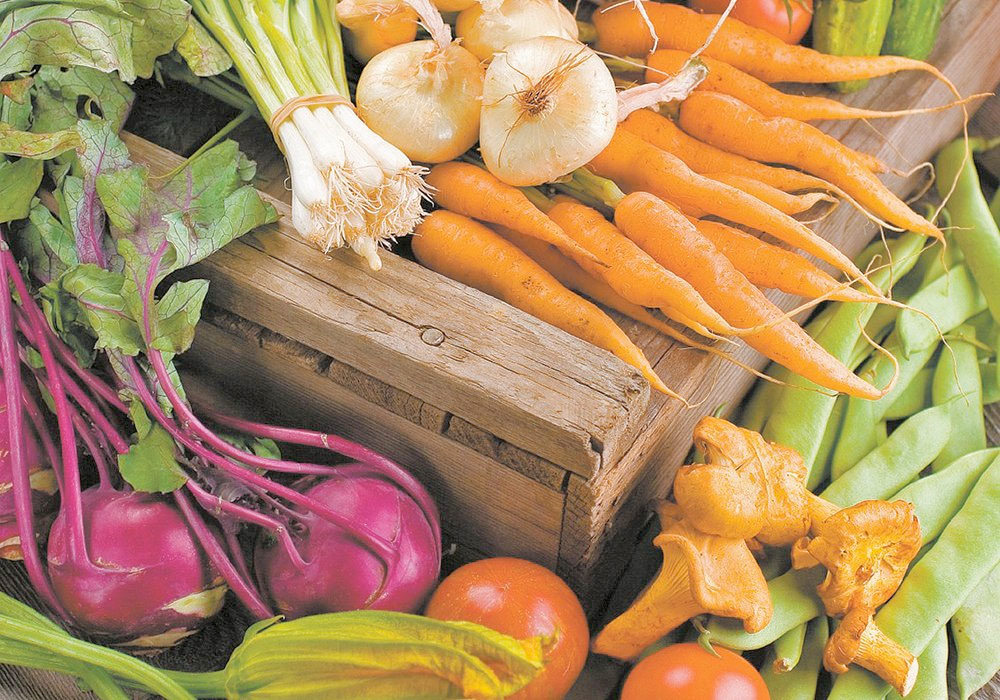 A variety of organic crops on display, including carrots, beets, tomatoes and onions.