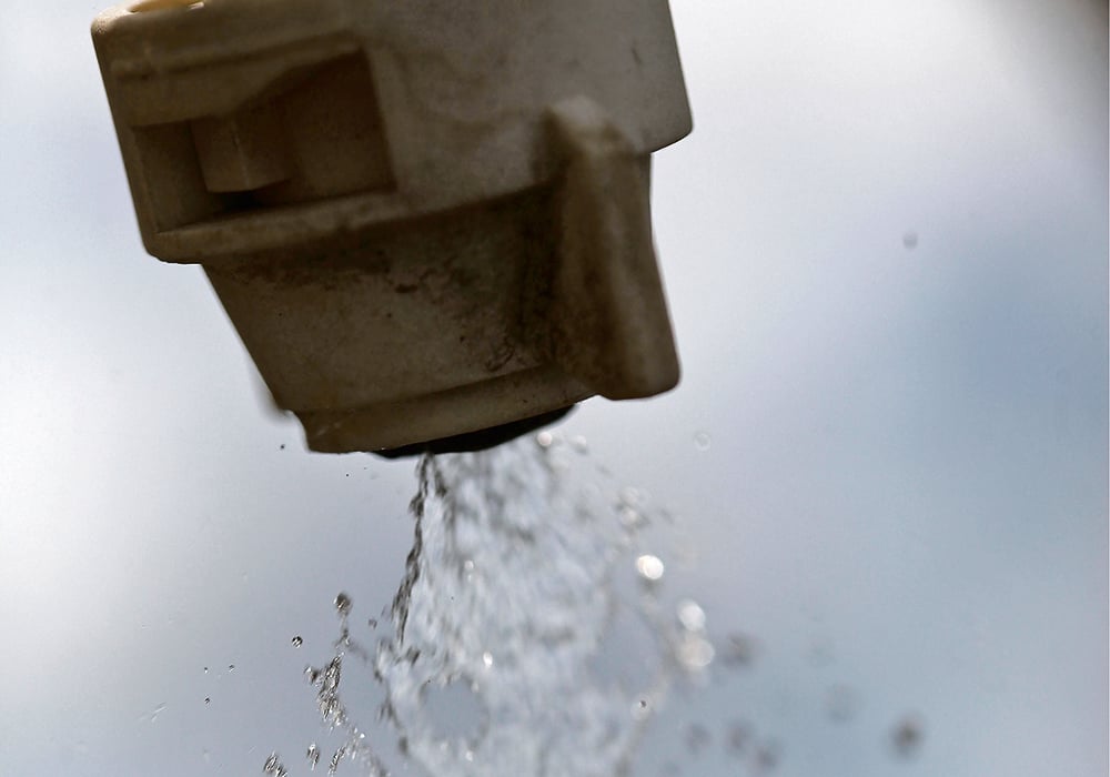 Close-up of a sprayer's nozzle tip with clear liquid coming out.