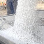 Fertilizer is dumped from a truck into an auger's hopper.