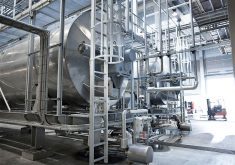 A large stainless steel tank is surrounded by a maze of pipes in a biomass refinery in Iowa.
