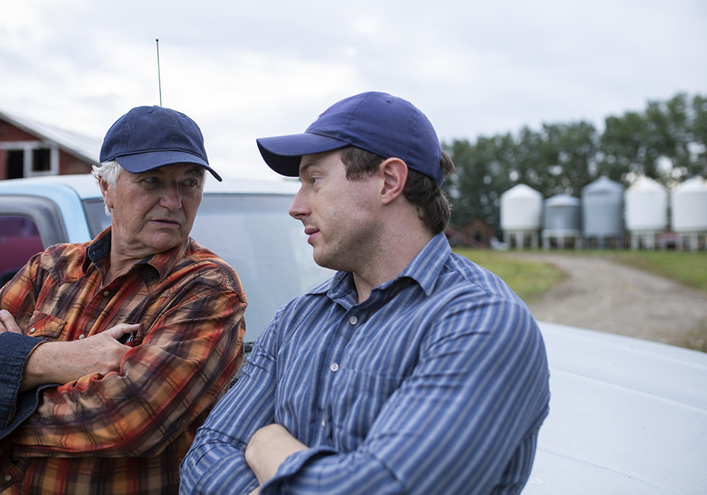 An older farmer and his twenty-something son chat on the farm.